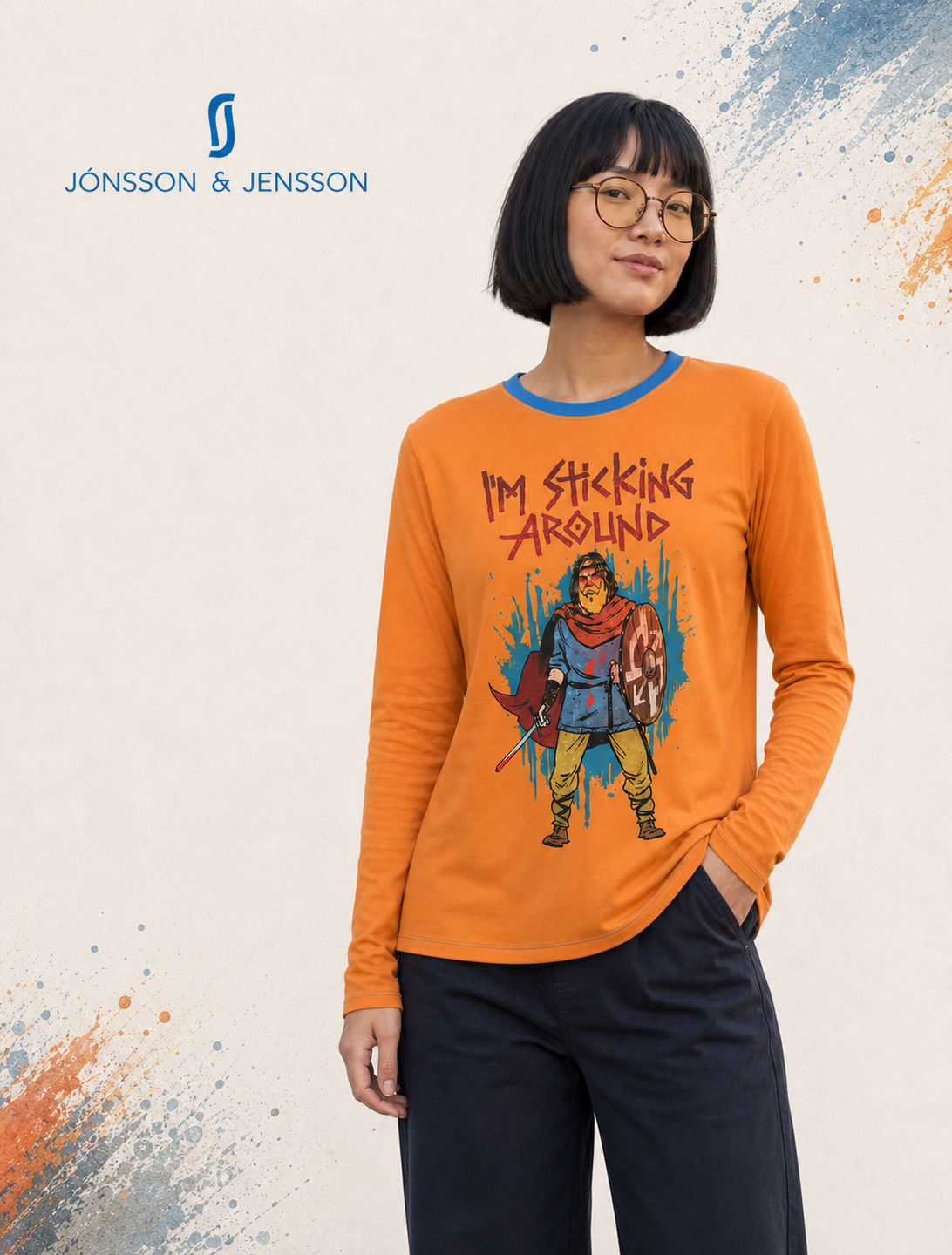 Woman wearing an orange long sleeve t-shirt with a picture of a stern looking Viking with the words "I'm sticking around" written above the character.