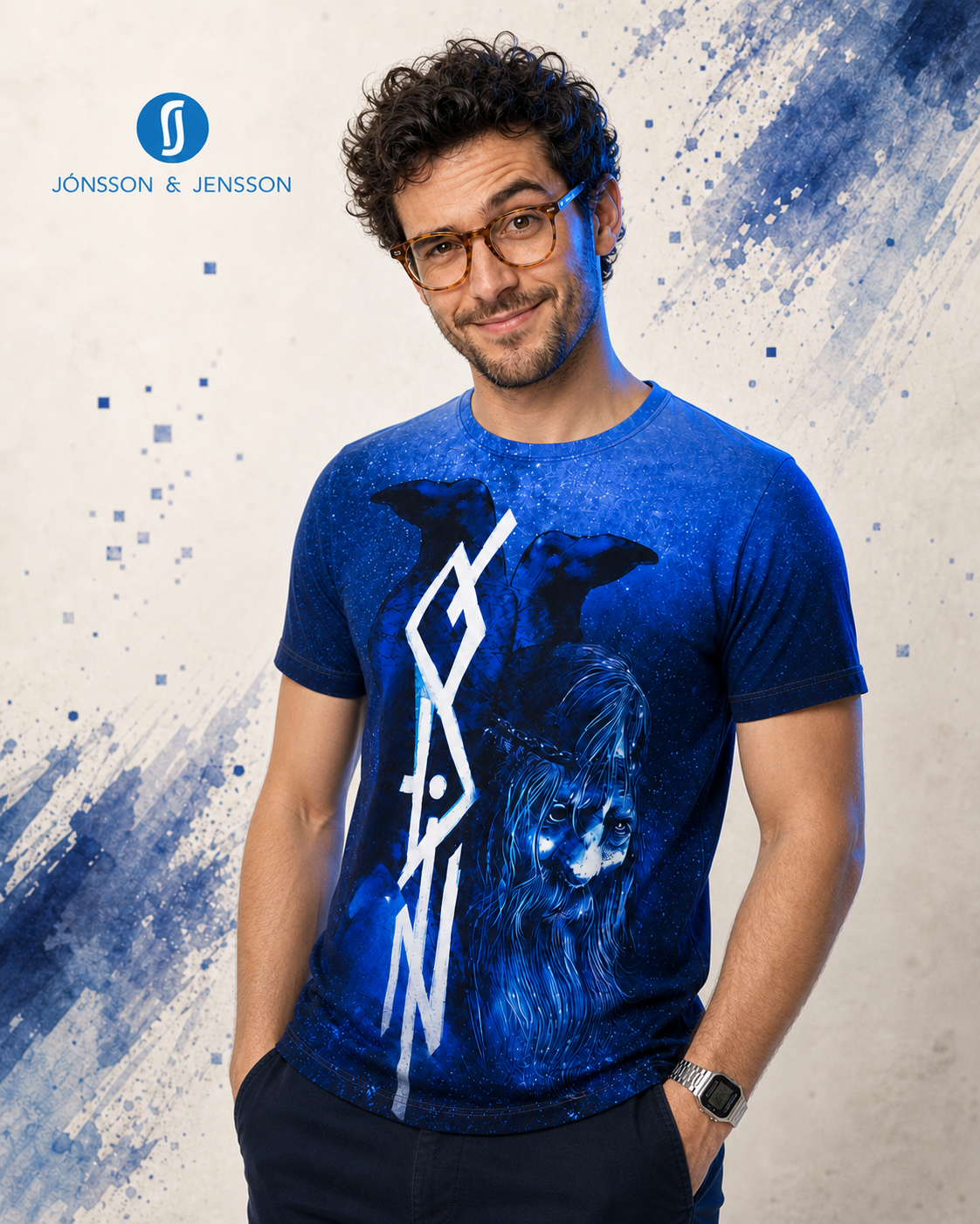 A man wearing a blue graphic t-shirt with a raven and white geometric design, posed against a textured light gray background with blue paint splatters.